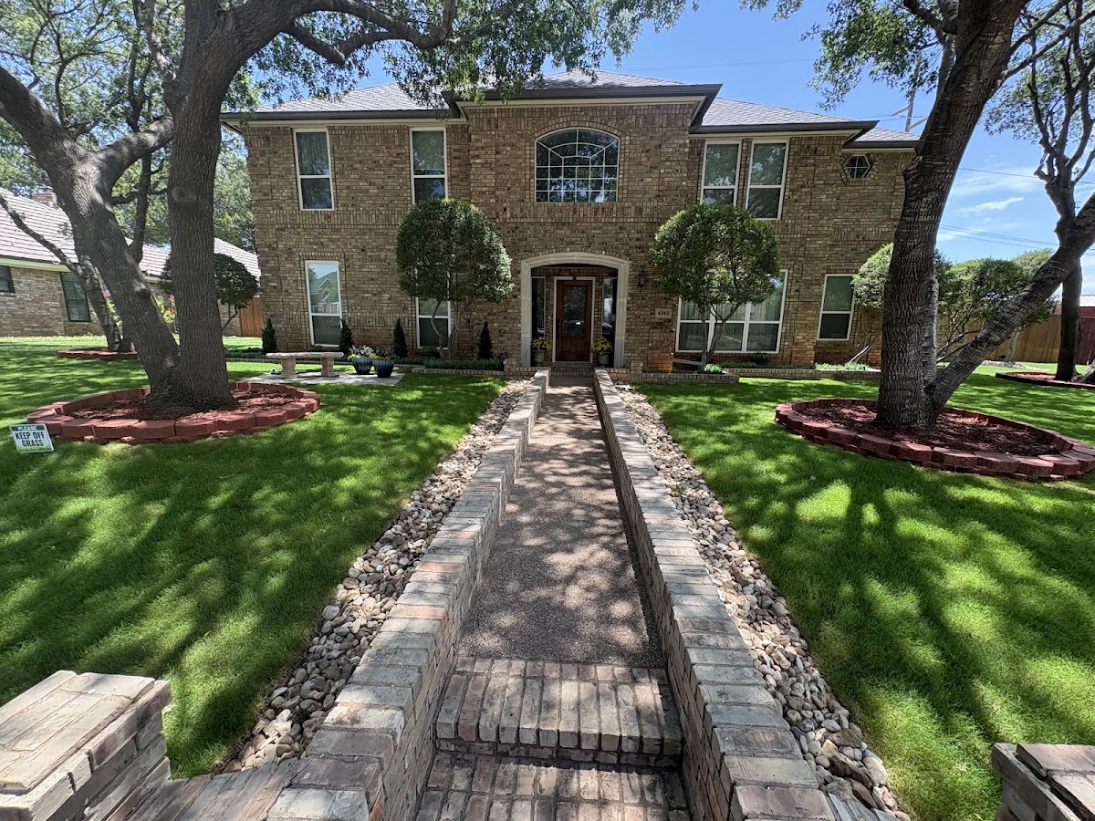 Two storey brick home with a manicured lawn and paver walkway