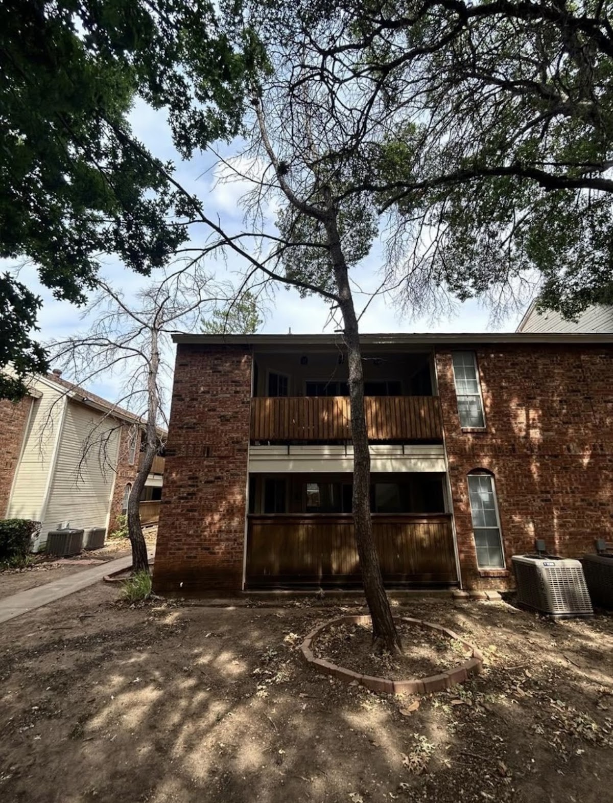 Brick apartment building with a trimmed tree and cleared grounds